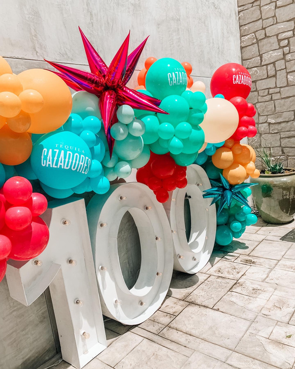 Brightly colored balloon garland displayed on top of marquee letters. 